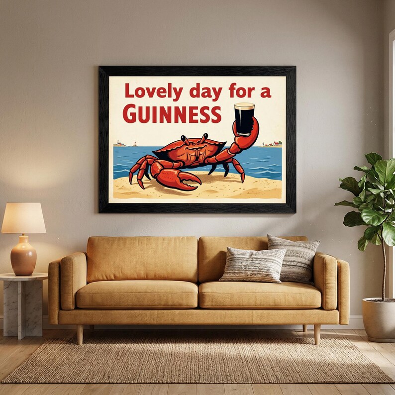 May include: A framed art print featuring a cartoon crab holding a pint of Guinness. The crab is red, set against a beach scene with the text "Lovely day for a Guinness" in red and white.