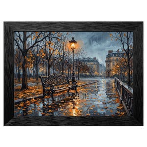 May include: A framed art print depicts a rainy autumn scene in a European city park. A black wrought-iron bench sits beneath a lit lamppost. Fallen leaves cover the wet pavement, reflecting the warm glow of the lights and buildings.