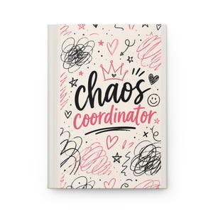 May include: A hardcover notebook with a cream-colored cover. The cover features the words "chaos coordinator" in black and pink script, along with doodles of hearts, stars, and scribbles. A crown graphic sits above the word "chaos".