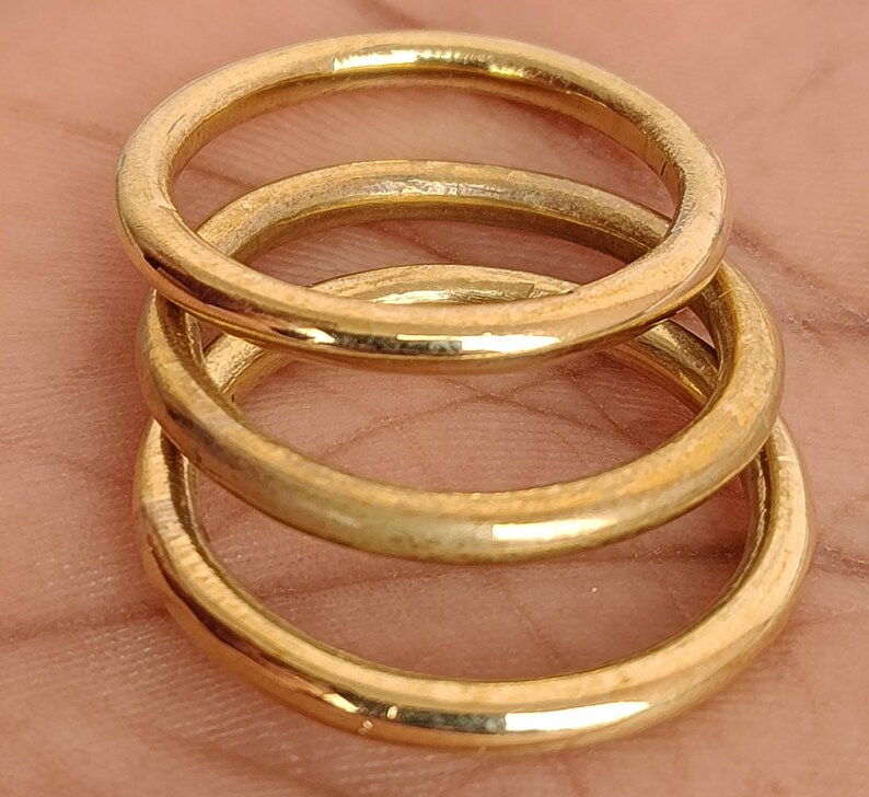 May include: Three gold-coloured rings stacked on top of each other. The rings are circular and appear to be made of metal. The rings are a warm, golden colour and have a slightly worn appearance.