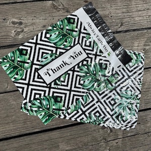 May include: Two poly mailer envelopes with a black and white geometric pattern and green monstera leaves. One envelope has a white label that says "Thank You". The other envelope has the text "Always Earth Day".