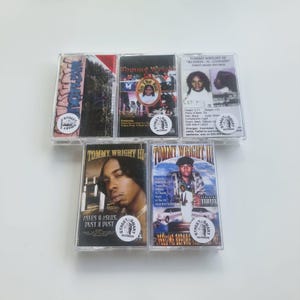 May include: A collection of five cassette tapes featuring album art with text and images. The tapes are in clear plastic cases, with the artist's name and album titles visible. The Street Smart Records logo is on each tape.