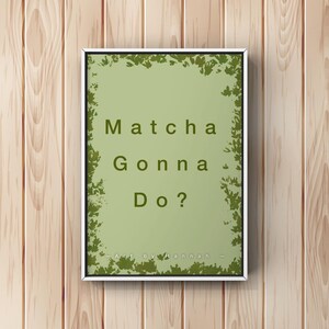 Puede incluir: Un cuadro rectangular con marco que presenta un fondo verde salvia claro con un borde de hojas verde oliva oscuro. El texto "Matcha Gonna Do?" está centrado en verde oliva oscuro, con "- Art by Hannah -" impreso en la parte inferior.