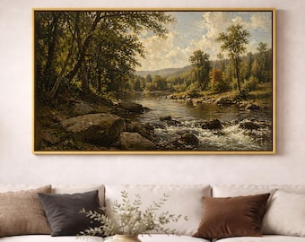 May include: A rectangular landscape painting in a gold frame depicting a river flowing through a forest with large rocks in the foreground, green trees, and a cloudy sky. The artwork features natural tones of green, brown, and blue throughout.