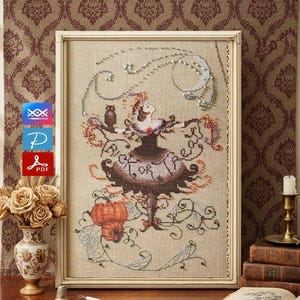 May include: A framed cross-stitch depicting a woman in a dress with the text "RICE OR" on the skirt. The artwork features an owl, a crescent moon, and floral elements in shades of brown, beige, and red. The frame is a light beige color.