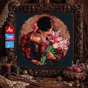 Puede incluir: Patrón de punto de cruz de una mujer con flores, enmarcado en un marco de madera oscuro y ornamentado. La mujer lleva un vestido rojo y una flor en el pelo. El fondo es de color verde azulado oscuro con un efecto de halo dorado.