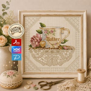 Puede incluir: Un bordado en punto de cruz enmarcado que muestra una taza de té con la palabra Mother, rosas rosadas y un patrón de tapete de encaje. La pieza se exhibe con un alfiletero, tijeras de metal y botones.