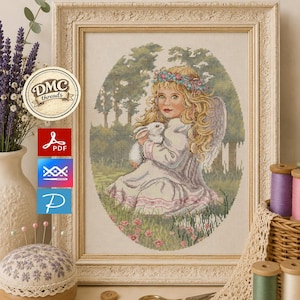 Puede incluir: Obra de arte en punto de cruz enmarcada de una niña con alas de ángel sosteniendo un conejo blanco. La niña lleva una corona de flores y un vestido blanco con ribetes rosas. El marco es adornado y color crema.