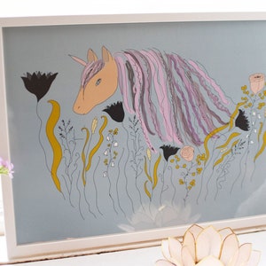 May include: A framed illustration of a pink and purple unicorn with a gold horn, surrounded by yellow, black, and white flowers on a light blue background.