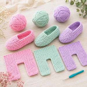 May include: Three pairs of crocheted baby booties and matching pants in pink, mint green, and lavender. Each set is accompanied by a corresponding ball of yarn. A single teal crochet hook is positioned at the bottom right of the arrangement.