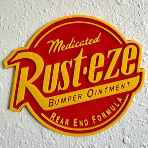 May include: A red and yellow sign with the text "Medicated Rust-eze Bumper Ointment Rear End Formula". The sign has a rounded shape with a yellow border and yellow lettering.