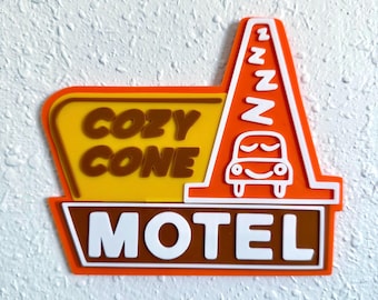 May include: An orange, yellow, and brown Cozy Cone Motel sign. The sign features the words "COZY CONE" and "MOTEL" in white lettering. A cartoon car is sleeping under a series of Z's.