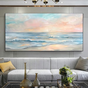 Può includere: Grande dipinto ad olio rettangolare di un paesaggio marino. L'opera raffigura una spiaggia con onde nelle tonalità del blu e del bianco, sotto un cielo dai toni rosa, pesca e blu. Il dipinto è incorniciato in nero e appeso sopra un divano grigio.