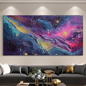 May include: Large abstract canvas art featuring a vibrant depiction of a nebula. The artwork showcases a blend of colors, including deep blues, purples, pinks, and yellows, with white speckles. The textured surface adds depth to the cosmic scene.