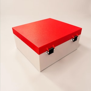 May include: A rectangular storage box with a red lid and white base. The lid has a textured surface and is secured by two black metal clasps. The box is designed for storage and organization.