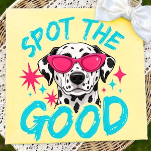 May include: A square yellow sign featuring a black and white spotted Dalmatian dog wearing bright pink cat-eye sunglasses. The text "SPOT THE GOOD" is printed in a bold, textured cyan font. Pink and cyan star shapes surround the dog's head.