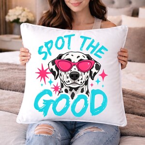 May include: A square white throw pillow featuring a graphic of a Dalmatian dog wearing bright pink cat-eye sunglasses. The text "SPOT THE GOOD" is printed in a bold cyan blue font above and below the dog, accented by small pink and blue stars.