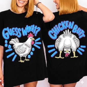 Może przedstawiać: Czarny t-shirt z białą grafiką kurczaka i napisem "Guess What?" z przodu oraz "Chicken Butt" z tyłu. Projekt zawiera niebieskie akcenty, tworząc humorystyczny i zabawny wygląd.