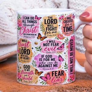 May include: A white ceramic mug featuring colorful watercolor-style patches with inspirational Bible verses and butterfly illustrations. The text includes phrases like I can do all things through Christ, The Lord will fight for me, and Fear is a liar.