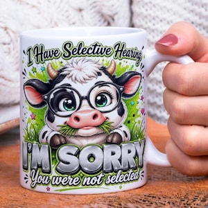 May include: White ceramic mug featuring a cartoon cow wearing glasses and holding grass in its mouth. The mug has the text "I Have Selective Hearing" and "I'M SORRY You were not selected" printed on it. The cow is black and white with green eyes.