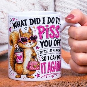 May include: A white ceramic mug featuring a cartoon squirrel wearing pink heart-shaped sunglasses, holding a pink coffee cup and a pink quilted handbag. The text reads: WHAT DID I DO TO PISS YOU OFF PLEASE LET ME KNOW SO I CAN DO IT AGAIN!