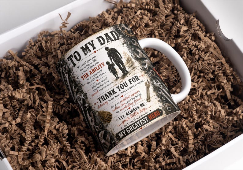 May include: A white ceramic mug with a handle, featuring a design with the text "TO MY DAD" and a silhouette of a father and child. The mug is in a white gift box filled with brown paper. The mug is approximately 4 inches tall.
