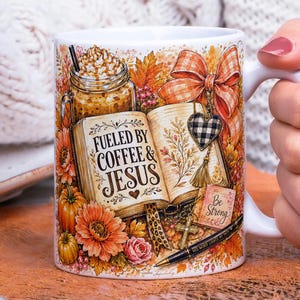 May include: A white ceramic mug featuring a colorful autumn-themed illustration of an open book with the text FUELED BY COFFEE & JESUS, a mason jar of coffee, a plaid bow, a heart charm, a cross, a pen, pumpkins, and fall flowers.