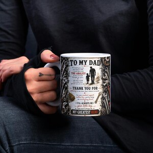 May include: White ceramic mug with the text "TO MY DAD" and a graphic of a father and child walking. The mug also includes the phrases "THE ABILITY", "THANK YOU FOR", "I'LL ALWAYS BE your little boy", and "MY GREATEST HERO".