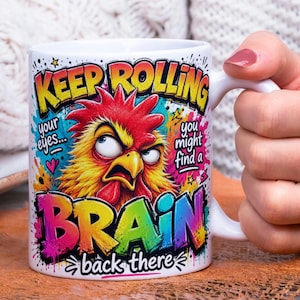 May include: White ceramic mug with a humorous design. The mug features a colorful illustration of an angry rooster and the text "KEEP ROLLING your eyes... you might find a BRAIN back there."