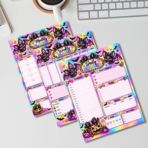 Peut inclure: Trois planificateurs en papier avec un fond holographique coloré orné de chauves-souris, de citrouilles et de cœurs. Les feuilles sont intitulées Monthly Planner, Weekly Planner et Daily Planner, avec des sections pour les tâches et repas.