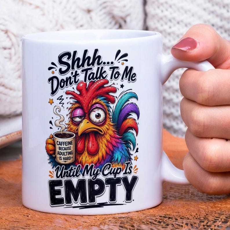 Op de afbeelding: Witte keramische mok met een kleurrijke haan illustratie en de tekst "Shhh... Don't Talk To Me Until My Cup Is EMPTY." De haan houdt een koffiekopje vast met de tekst "CAFFEINE BECAUSE ADULTING IS HARD."