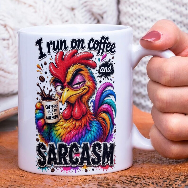 Op de afbeelding: Witte keramische mok met een kleurrijke haan illustratie. De haan houdt een koffiekopje vast en de mok leest "I run on coffee and sarcasm". De haan is rood, geel, blauw en paars.