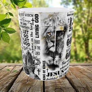 May include: White ceramic mug featuring a detailed graphic of a lion's face merged with Jesus, a cross, and praying hands. The mug includes religious text such as "Living God", "Jesus", and "King of Kings".
