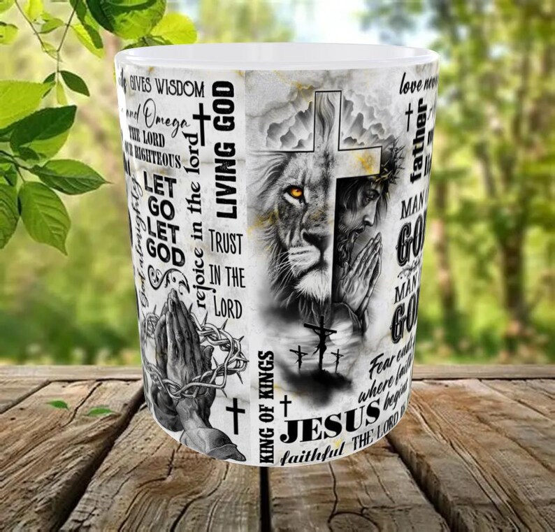 May include: White ceramic mug featuring a detailed graphic of a lion's face merged with Jesus, a cross, and praying hands. The mug includes religious text such as "Living God", "Jesus", and "King of Kings".