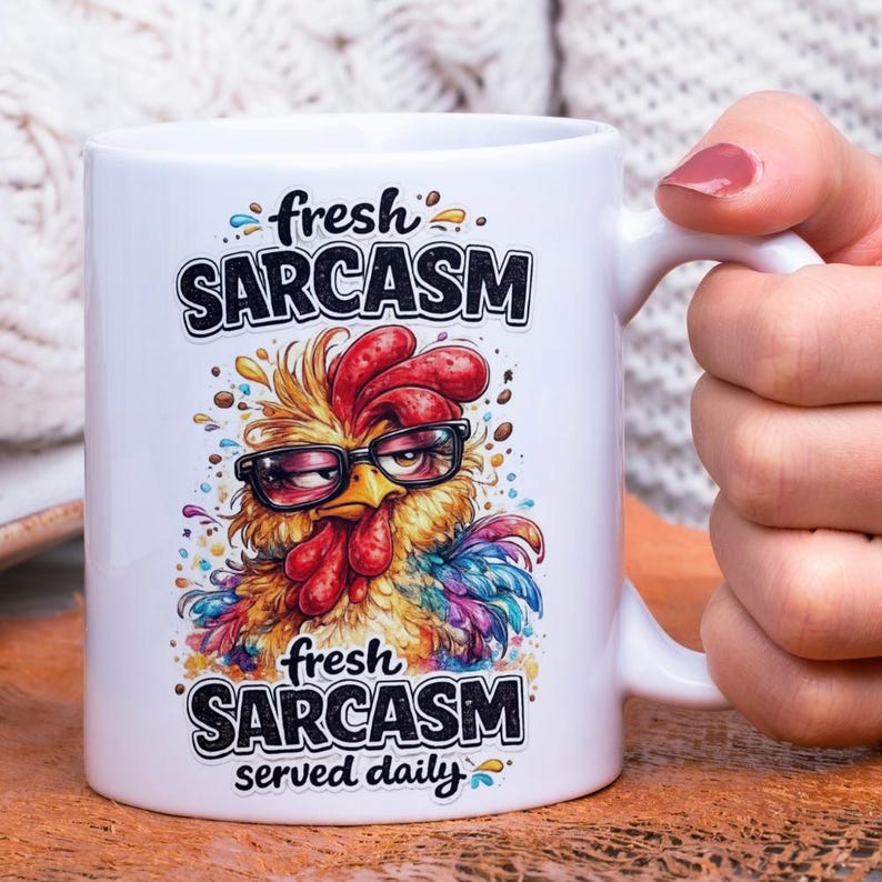 Op de afbeelding: Witte keramische mok met een humoristisch ontwerp. Het toont een cartoon haan met een bril, met de tekst "fresh SARCASM served daily". De haan is afgebeeld in levendige kleuren, waaronder geel, rood en blauw.