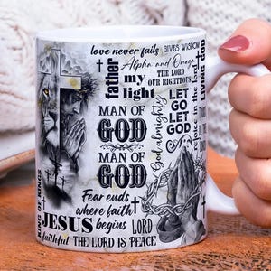 May include: White ceramic mug featuring religious imagery and text. The design includes a lion, a praying figure, and the words "Man of God," "Jesus," and other inspirational phrases. The mug has a white handle.