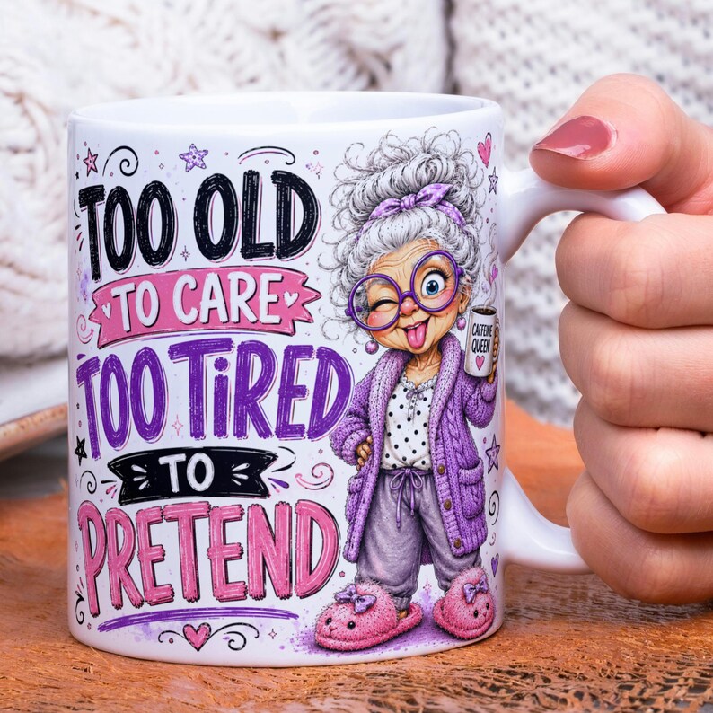 May include: A white ceramic mug featuring a cartoon illustration of an elderly person with gray hair, purple glasses, a purple cardigan, and pink slippers. The text reads: TOO OLD TO CARE, TOO TIRED TO, PRETEND, and CAFFEINE QUEEN on a small mug.