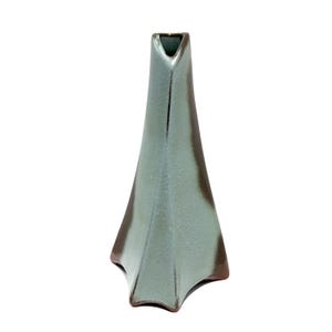 May include: A tall, ceramic vase with a unique, angular design. The vase has a light teal exterior with dark brown accents along the edges. The opening at the top is a narrow, triangular shape. The vase is suitable for displaying flowers or as a decorative item.