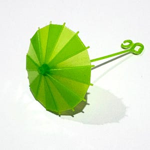 May include: A small, lime green cocktail umbrella pick featuring alternating translucent and opaque panels. The canopy is supported by thin plastic ribs, and the handle ends in a decorative loop, creating a classic drink garnish accessory.