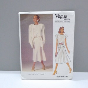 May include: Vogue Patterns sewing pattern featuring a John Anthony design. The cover shows illustrations of a white skirt suit and a white dress with a pink belt. The text "Vogue Patterns American Designer" is visible.