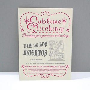 May include: A cream-colored sheet with the text "Sublime Stitching" in pink, along with "Dia de los Muertos" and various iron-on pattern designs. The sheet is 8 1/2" x 11" and suitable for embroidery and fabric painting.