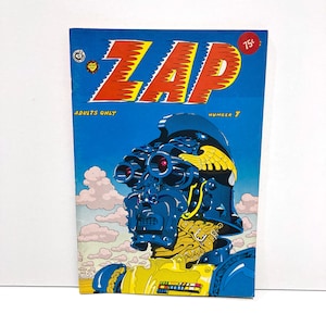 May include: A vintage comic book titled "ZAP" with a blue cover. The cover art features a blue robot-like figure with large goggles and a yellow uniform. The text "ADULTS ONLY" and "NUMBER 7" are also visible.