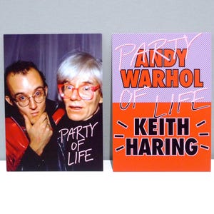 May include: Two postcards. One features a photo of two men, one wearing glasses and a shirt that says "Party of Life." The other postcard has the text "Party Warhol of Life Keith Haring" in orange and pink.