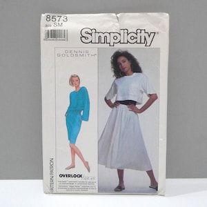 May include: A vintage Simplicity sewing pattern featuring two dress designs. The pattern includes a blue long-sleeve top and skirt, and a white crop top and skirt. The pattern is labeled "8573" and "Size SM".