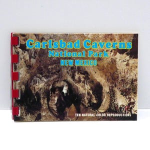 May include: A vintage travel souvenir booklet titled "Carlsbad Caverns National Park NEW MEXICO." The cover features a color photograph of the caverns and has a red binding. The text is in blue and yellow.