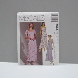 May include: A McCall's sewing pattern envelope featuring illustrations of women's dresses. The envelope is white with the McCall's logo and pattern number 2696. The dresses are various shades of purple with floral patterns.