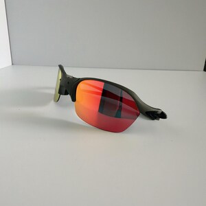 May include: Black sunglasses with red and orange gradient lenses. The sunglasses have a sleek, modern design with a black frame and a curved shape. The lenses transition from red to orange, offering a stylish look.