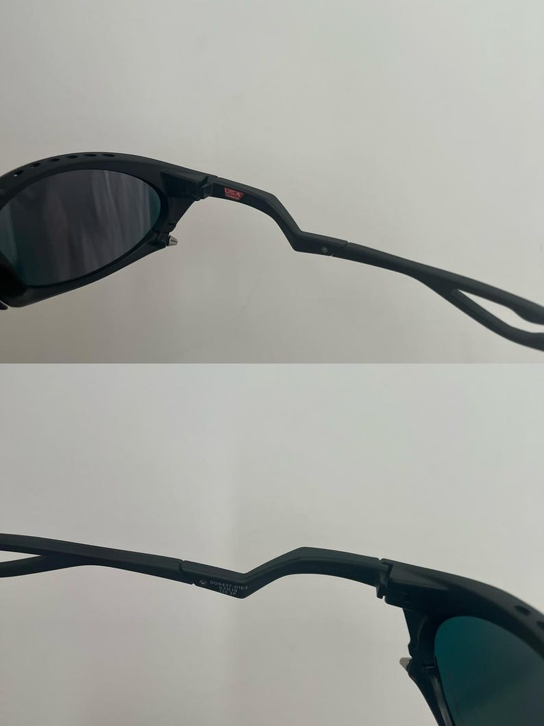 Może przedstawiać: Czarne okulary przeciwsłoneczne z ciemnymi soczewkami. Oprawki mają unikalny, kanciasty design z małym czerwonym logo "USA". Zausznik jest zakrzywiony i posiada zawias. Og&oacute;lny styl jest sportowy.