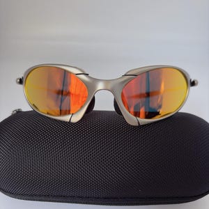 Gafas de sol retro Oakley Romeo X de metal con montura plateada mate y lentes polarizadas con degradado naranja, estilo vanguardista Y2K. imagen 1