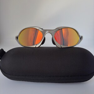 Gafas de sol retro Oakley Romeo X de metal con montura plateada mate y lentes polarizadas con degradado naranja, estilo vanguardista Y2K. imagen 2